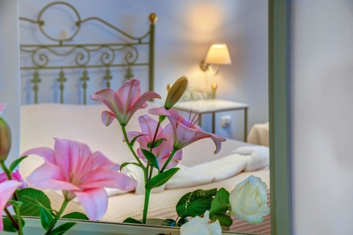 Une chambre à coucher avec un lit en métal, une table de chevet avec une lampe et des fleurs sur la table de chevet.
