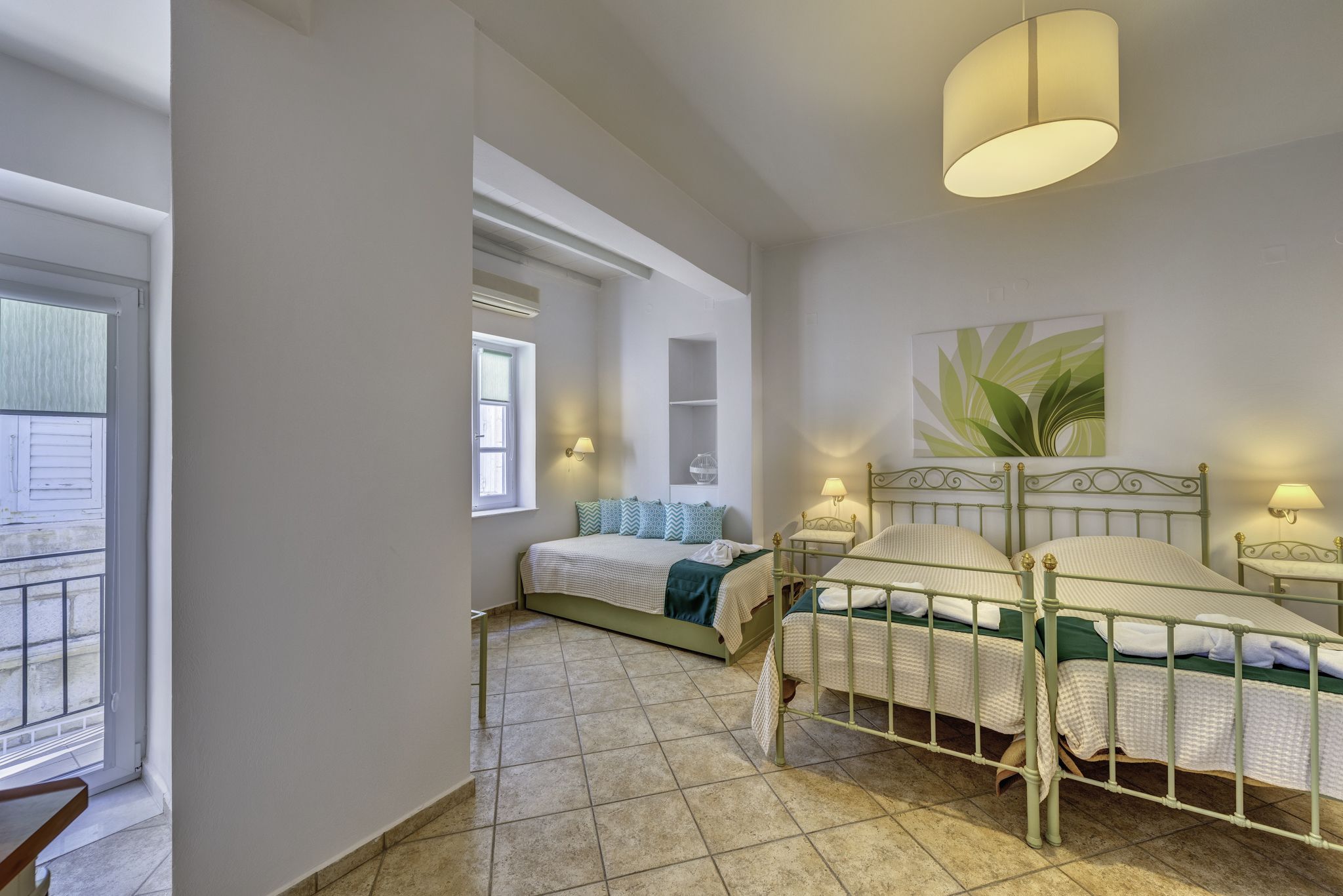 A bedroom with a large bed, two bedside tables with lamps, a window, and a ceiling light fixture.