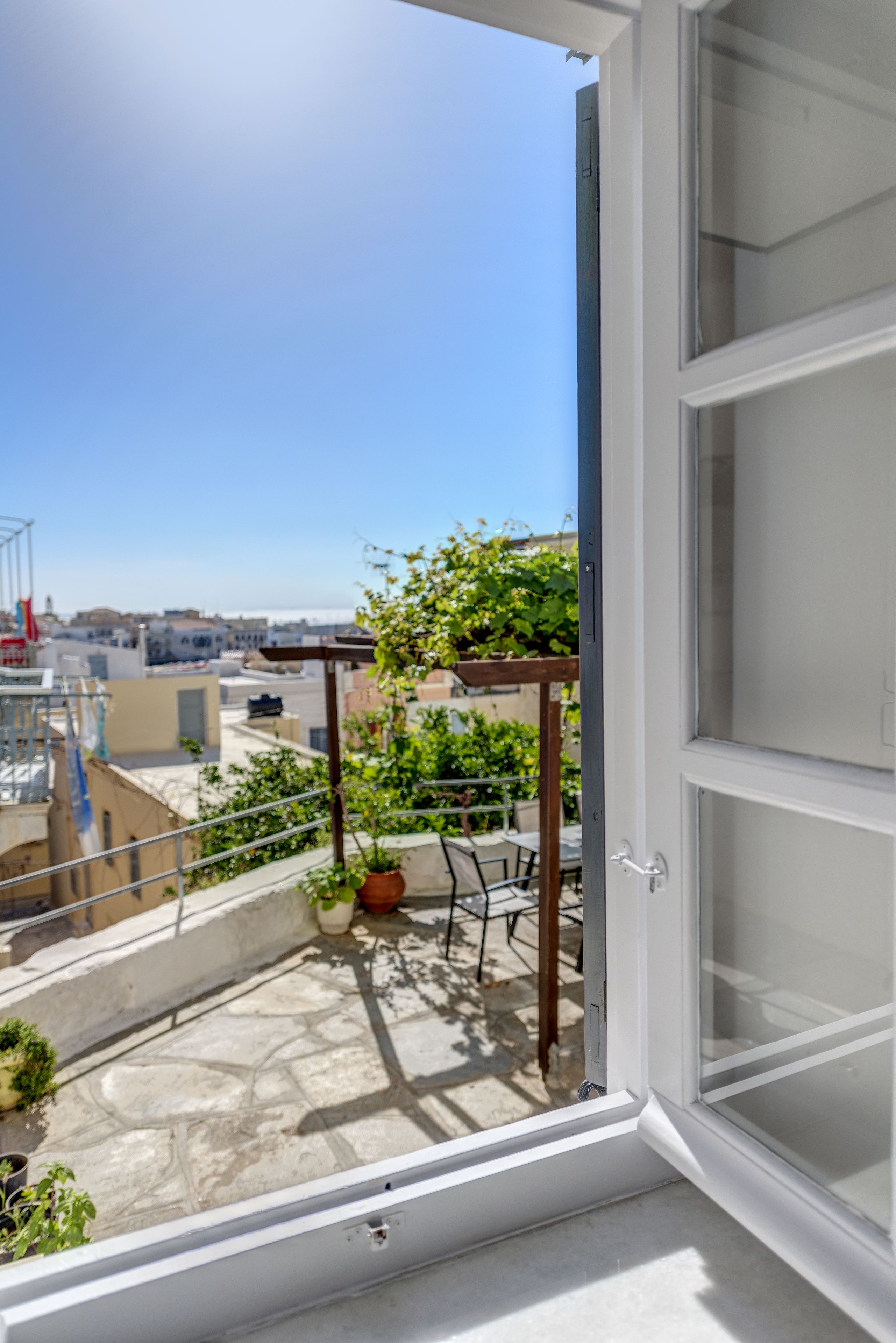 A balcony with a pergola, potted plants, and a view of the cityscape.