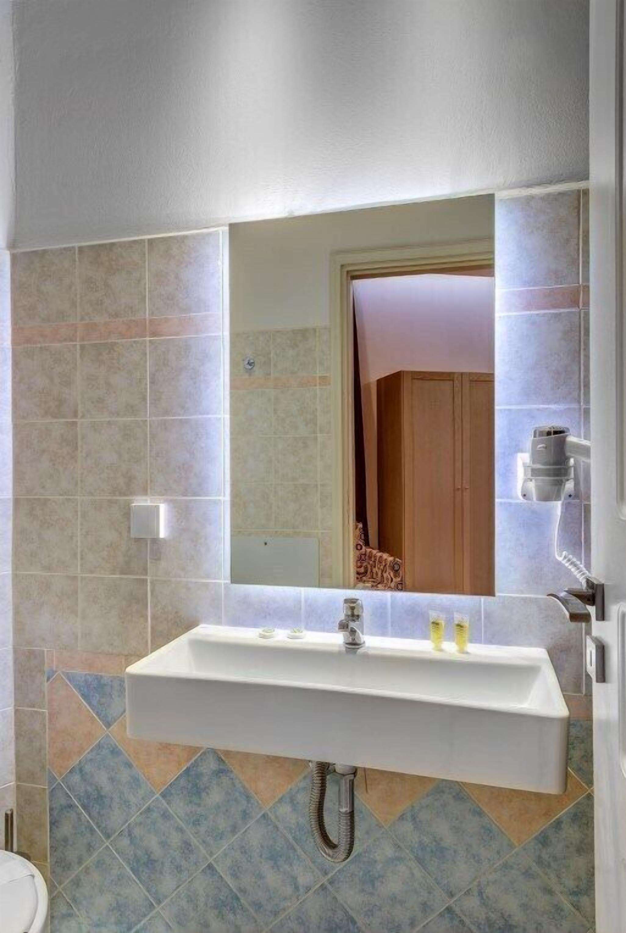 A bathroom with a white sink, a mirror, and a shower area.