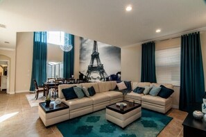 Uma sala de estar com sofá seccional, mesa de centro e um espaço de jantar com mesa e cadeiras.