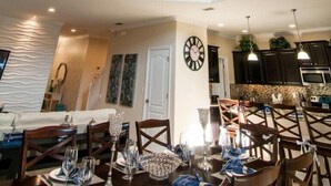 Un'ampia sala da pranzo con un lampadario, sedie in legno e un tavolo imbandito per un pasto.
