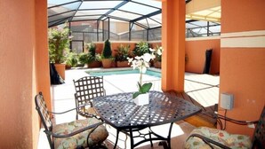 Una veranda con tavolo e sedie, una struttura in vetro e una piscina.