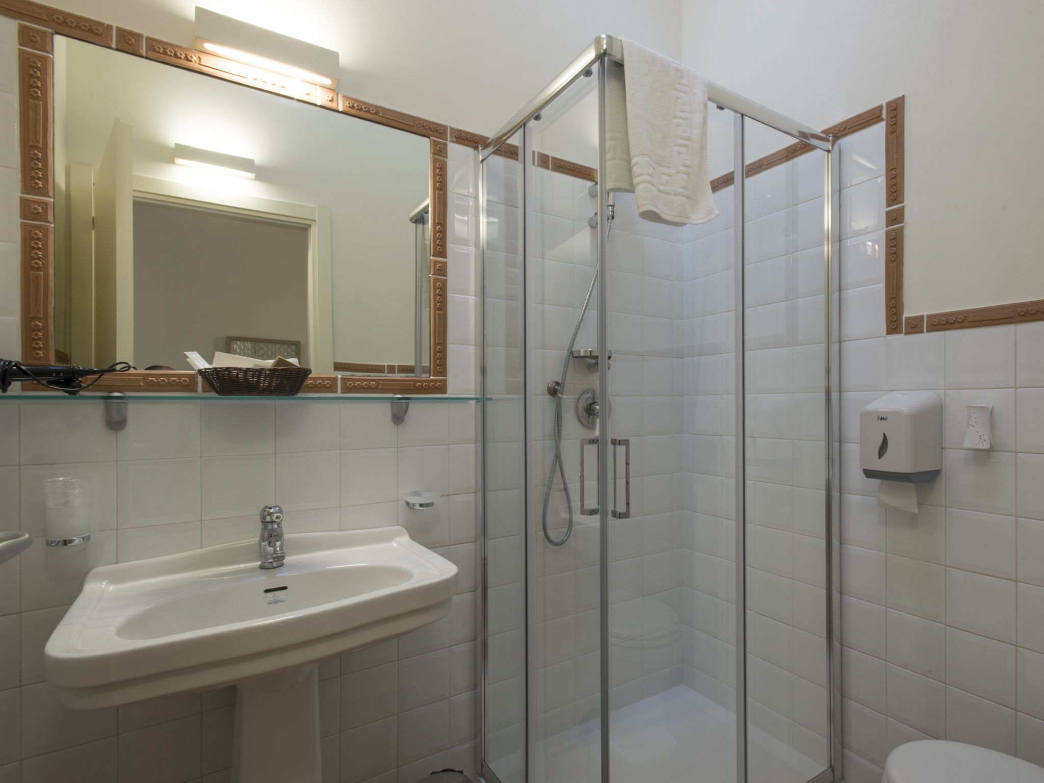 Un baño con cabina de ducha de vidrio, un lavabo con espejo y un inodoro.