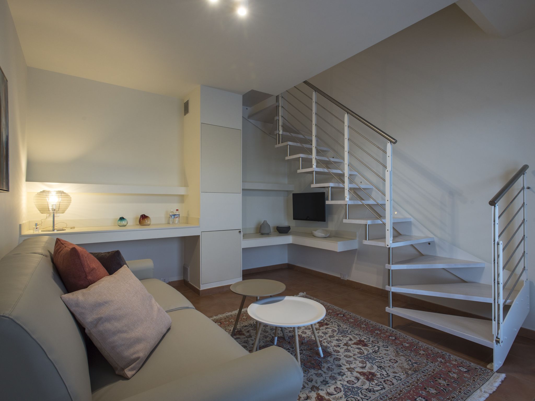 Un salon moderne avec un canapé, une table basse, un téléviseur et un escalier.
