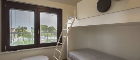 A bunk bed room with a window, a ladder, and a small round table.
