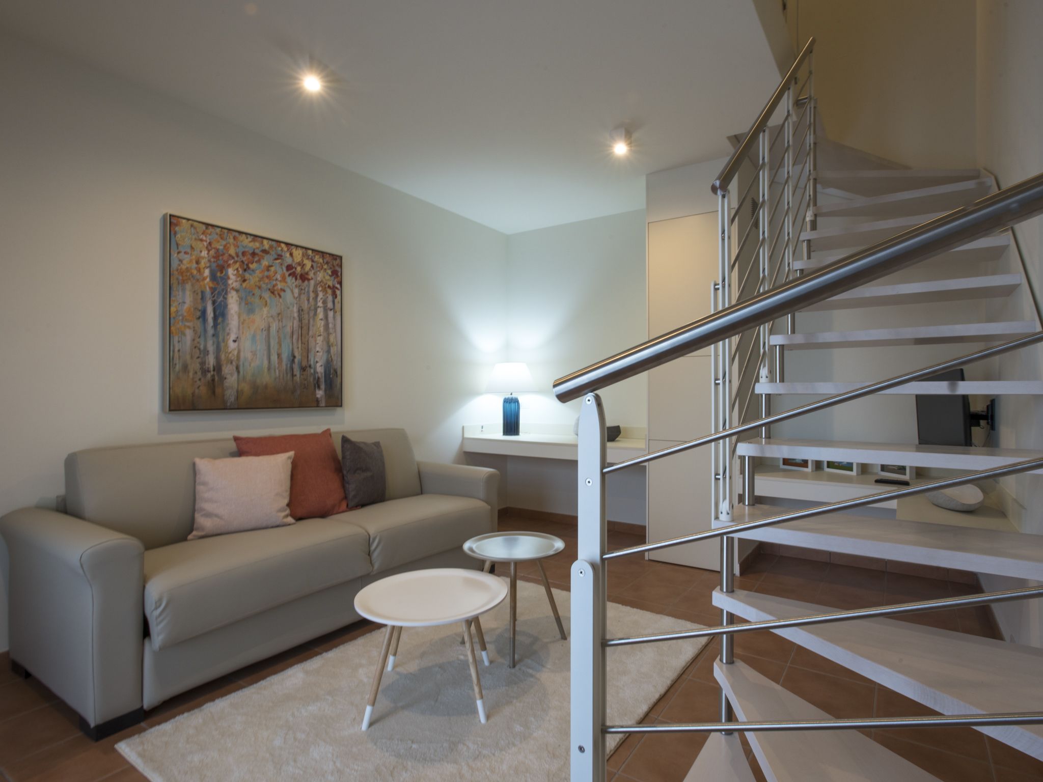 Una sala de estar moderna con un sofá, una mesita y una escalera.