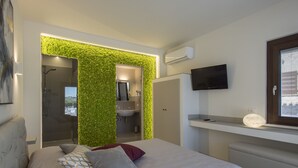 A modern bedroom with a bed, a TV, and a green wall. - Osteria dei Segreti (Appignano)