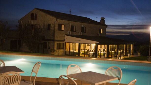 A large stone building with a swimming pool and outdoor seating area. - Osteria dei Segreti (Appignano)