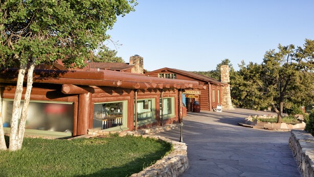 A rustic log cabin with a stone chimney, a covered porch, and a well-maintained lawn.