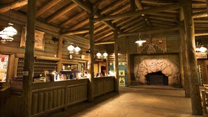 A rustic interior with wooden beams, a stone fireplace, and a reception desk.