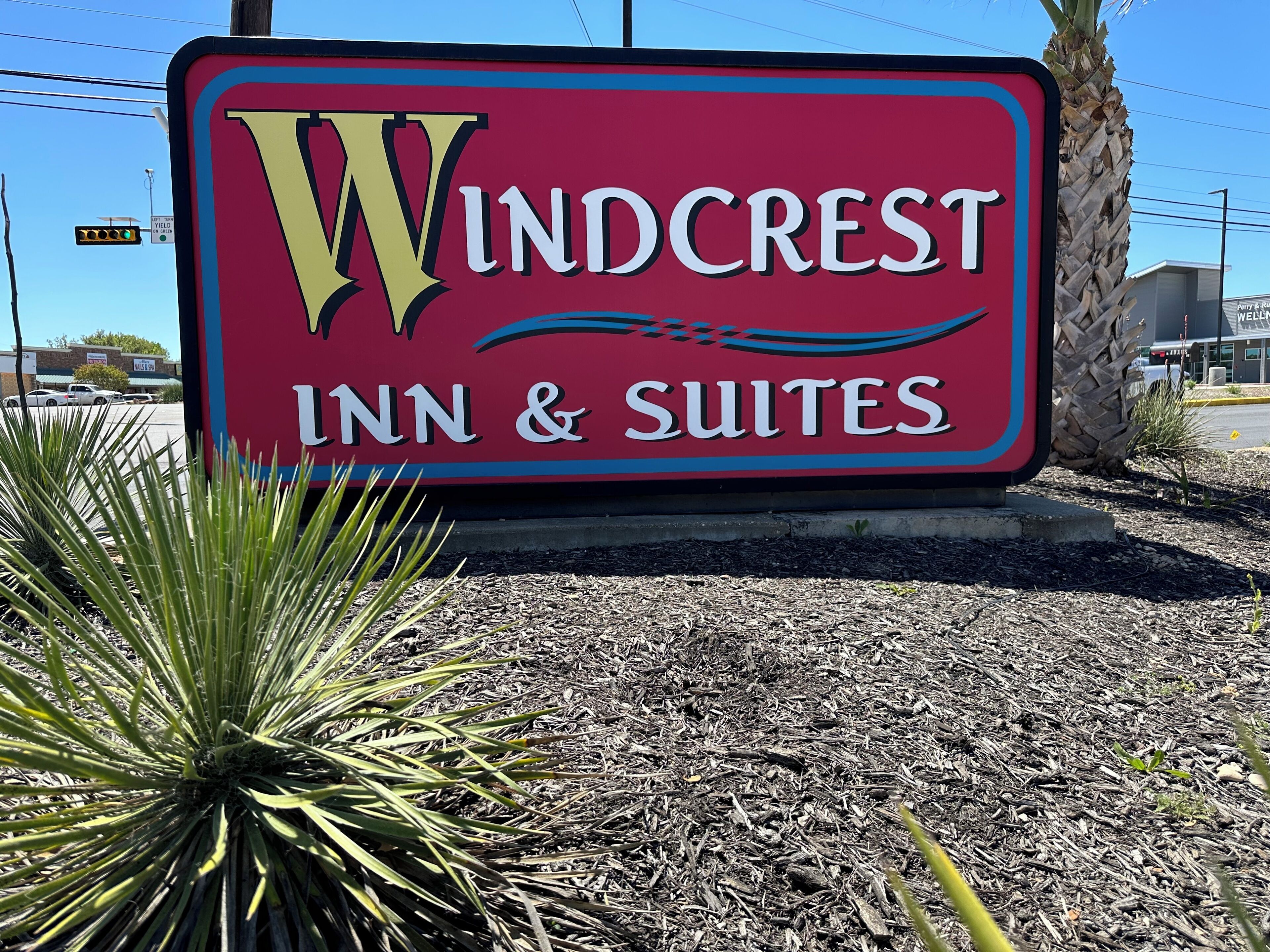 Une enseigne pour le Windcrest Inn & Suites, avec un logo en forme de « W » bien visible.