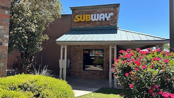 Een SUBWAY restaurant met een gevel van baksteen en een groen luifel.