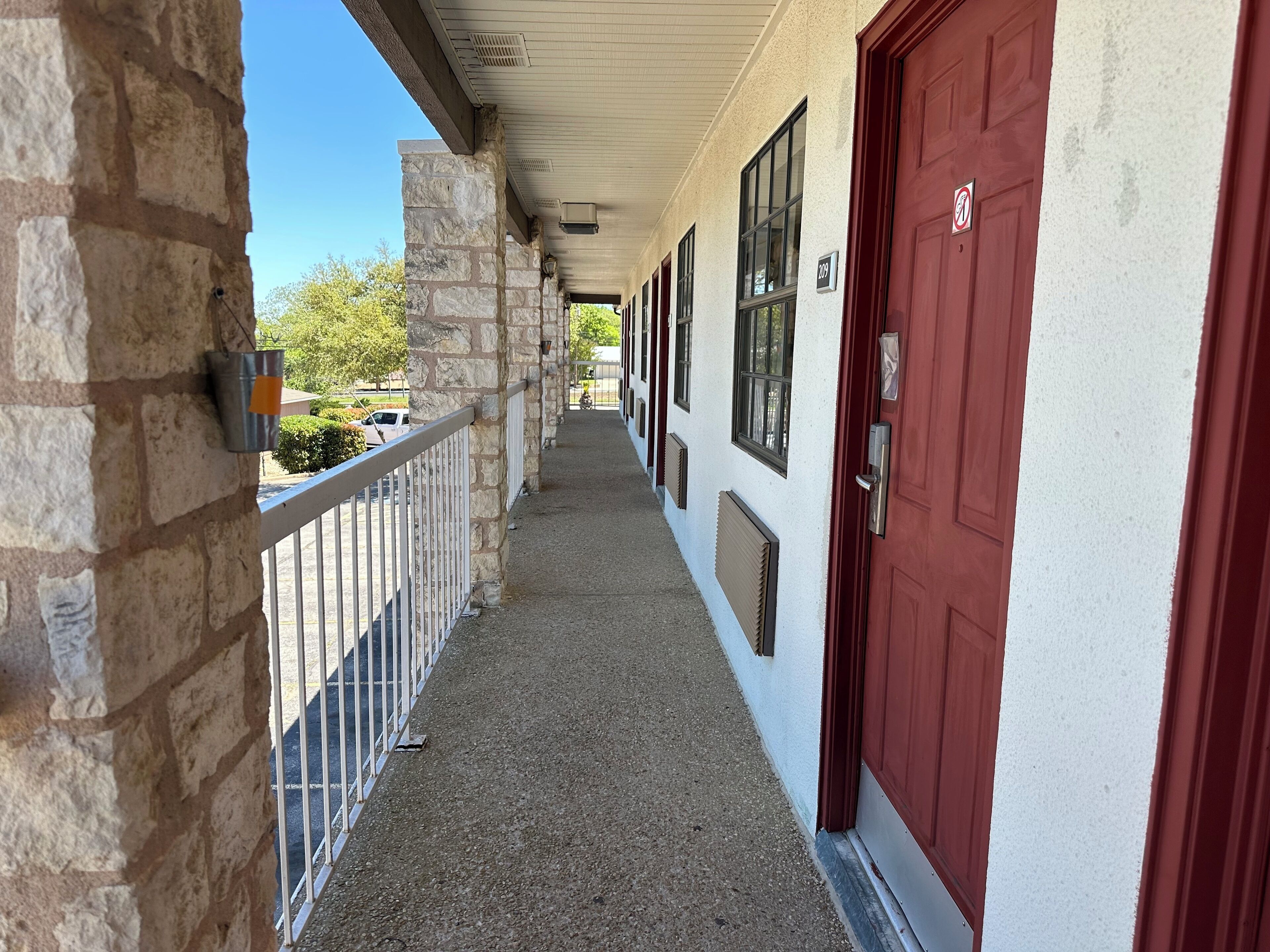 A corridor with stone walls, a metal railing, and red doors.