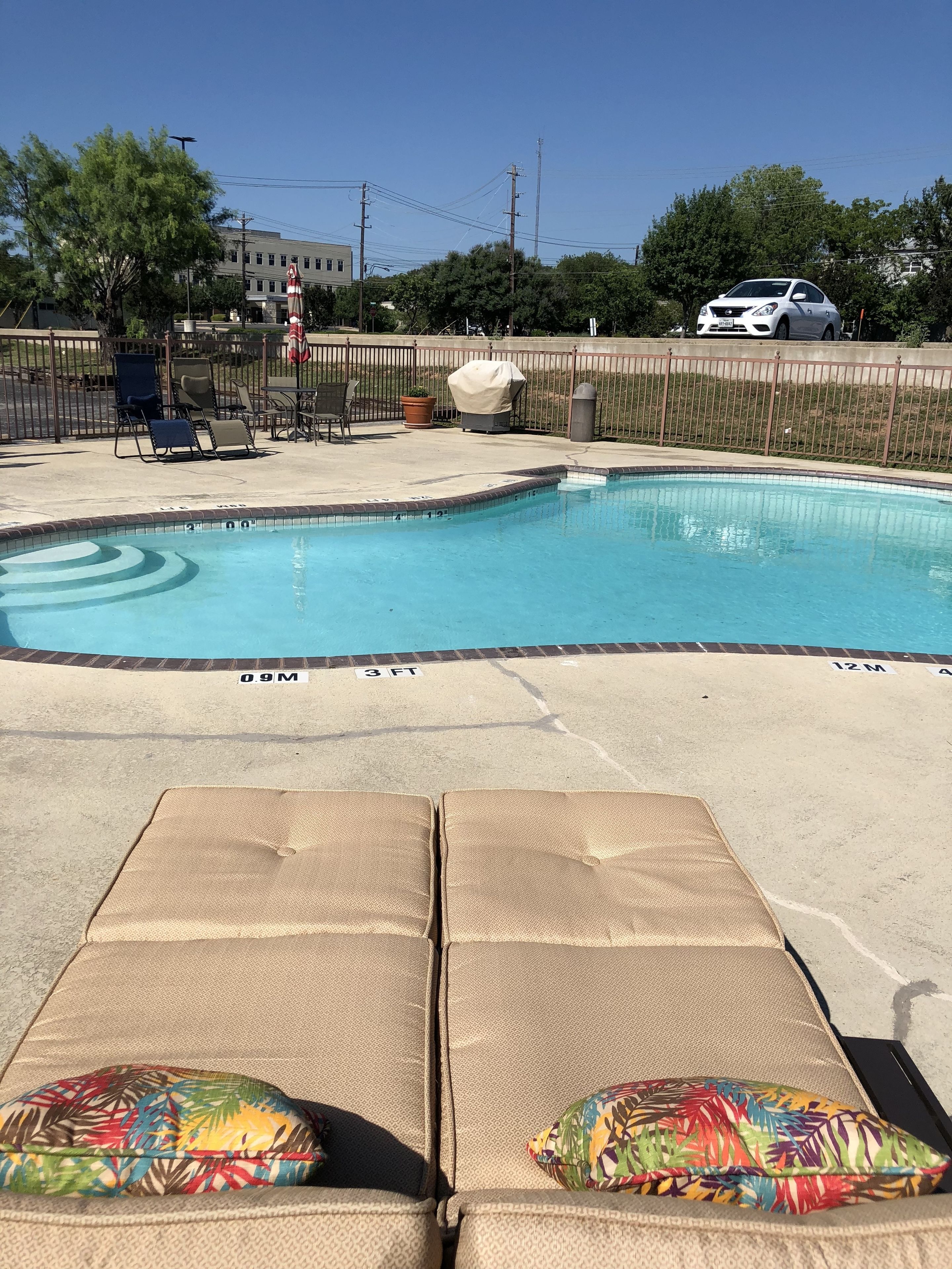 A swimming pool with lounge chairs and a covered grill area.