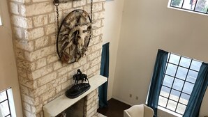 Una sala de estar con chimenea de piedra, dos sillones, una mesa de centro y una alfombra estampada.
