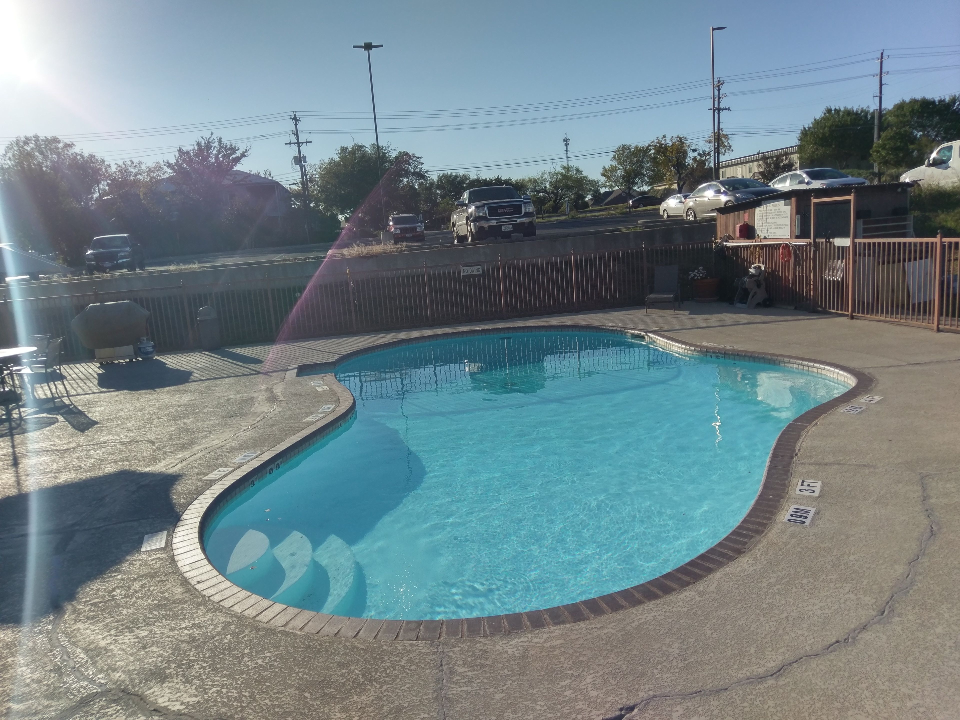 En swimmingpool med en buet kant, omgivet af en betonflisebelagt terrasse.