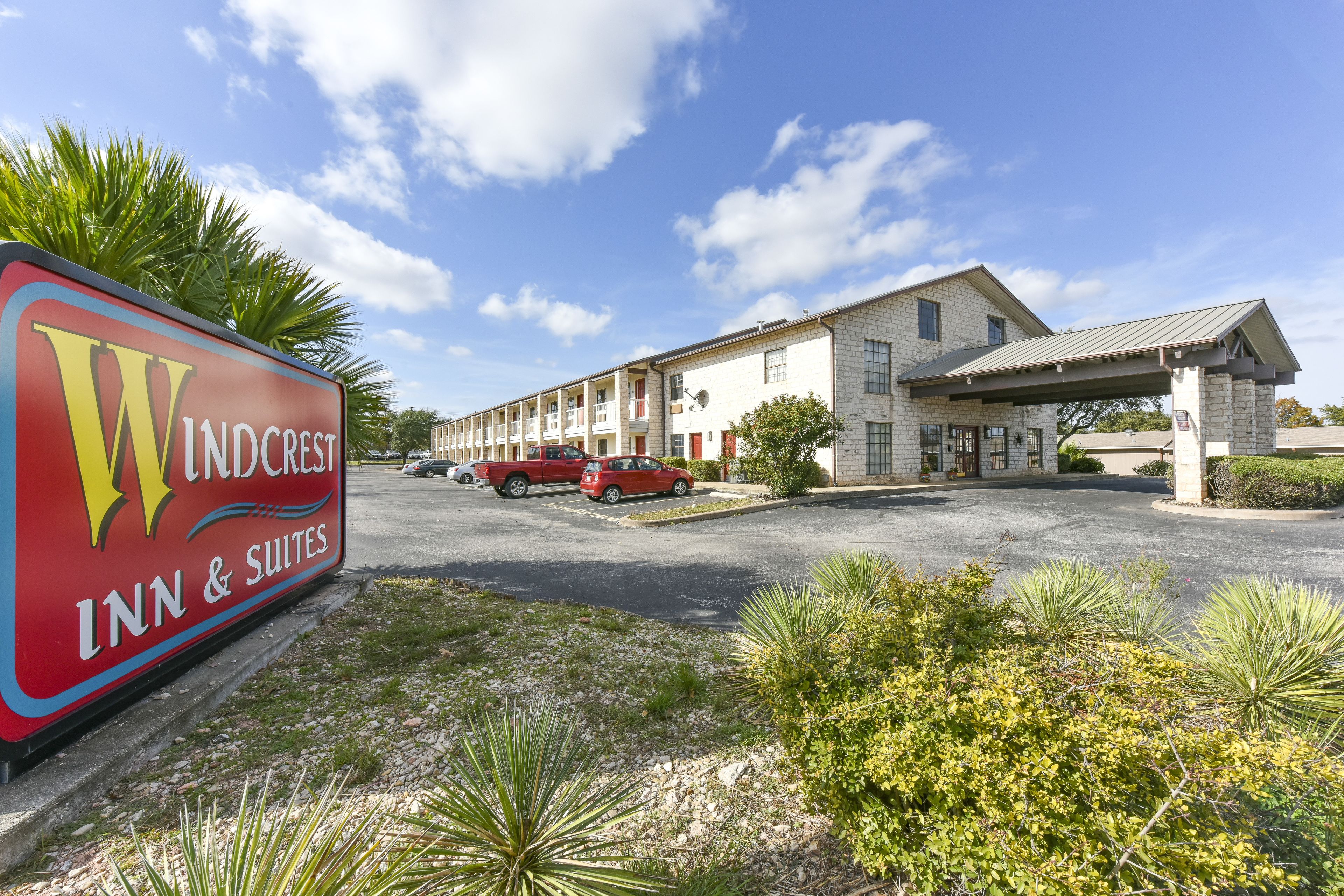 Edifici del Windcrest Inn & Suites amb un pàrquing i un cartell.