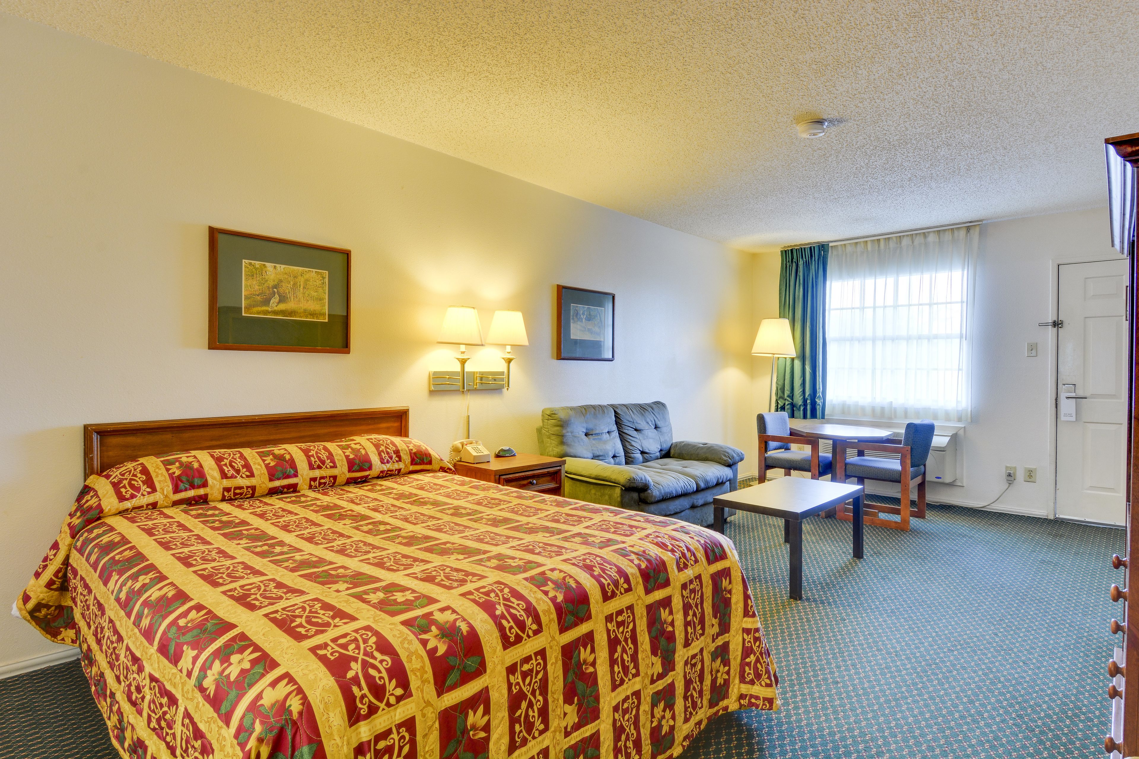 Een hotelkamer met een groot bed, een bureau, een stoel en een raam met gordijnen.