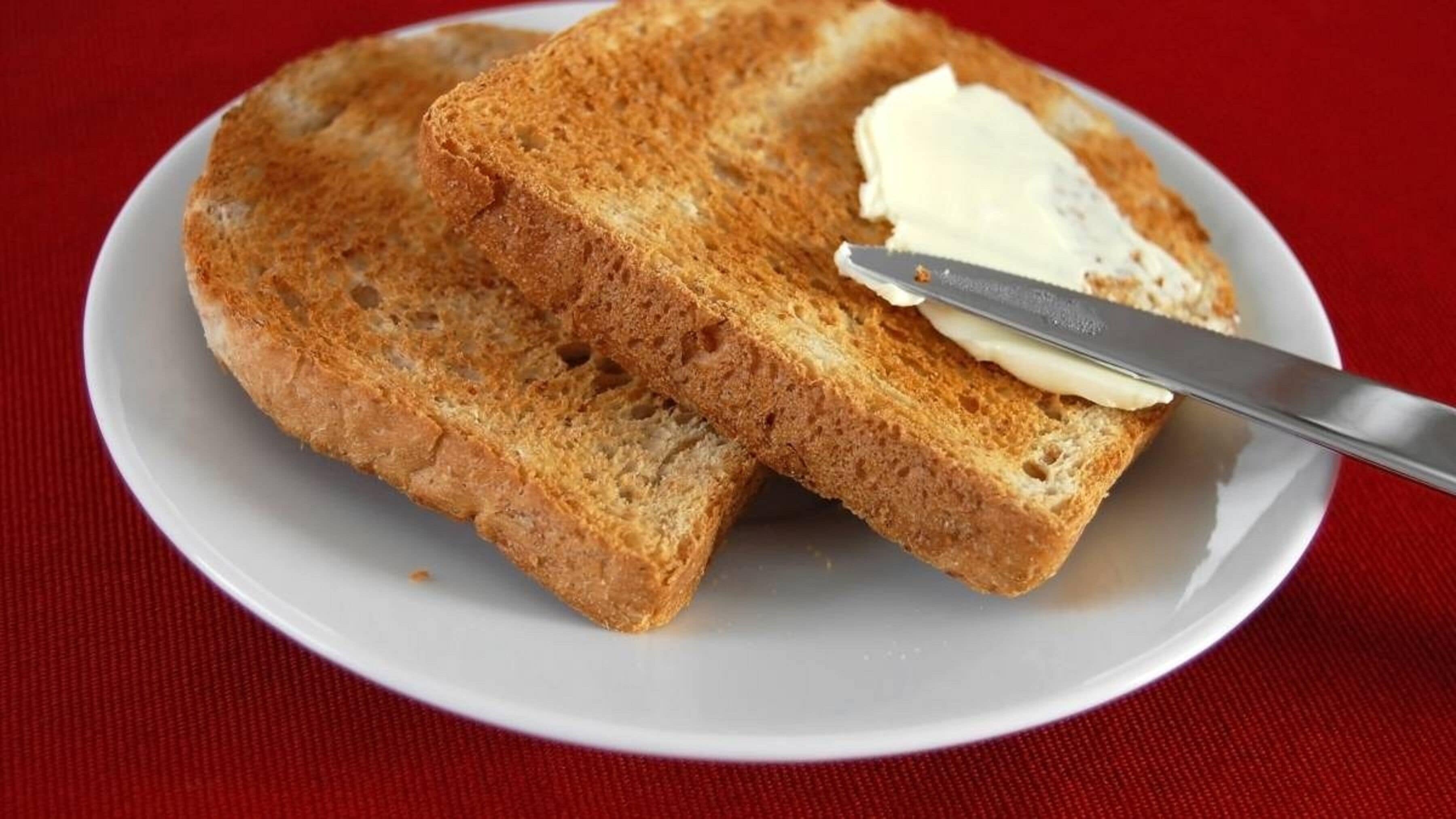 Deux tranches de pain grillé, beurrées, sur une assiette blanche.