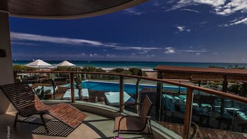Uma varanda com piscina, espreguiçadeiras e vista para o oceano.