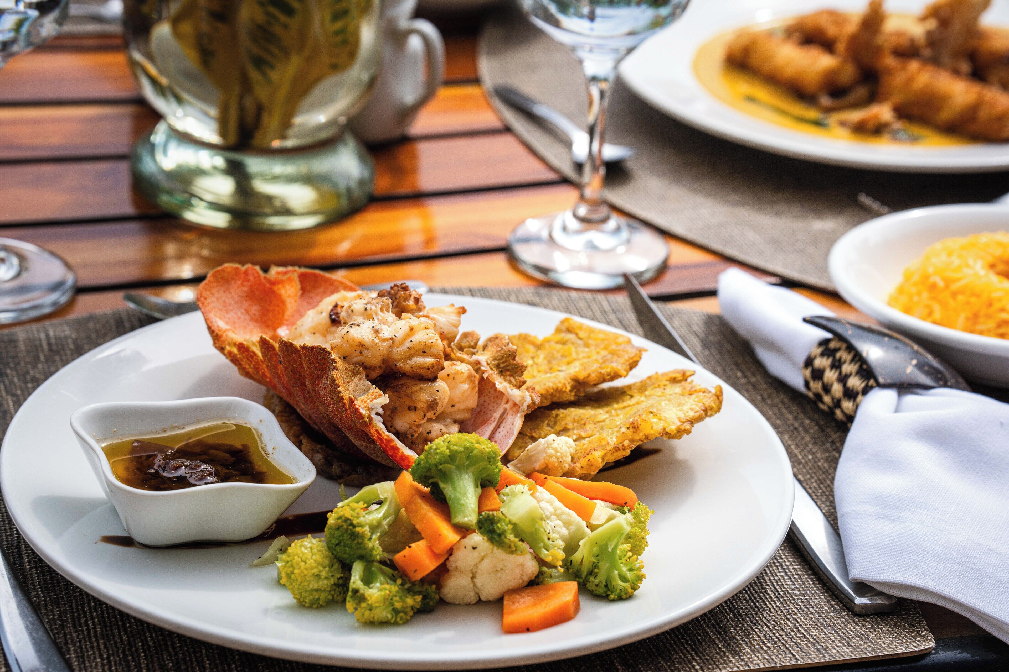 A plate of food with vegetables and a small bowl of sauce.