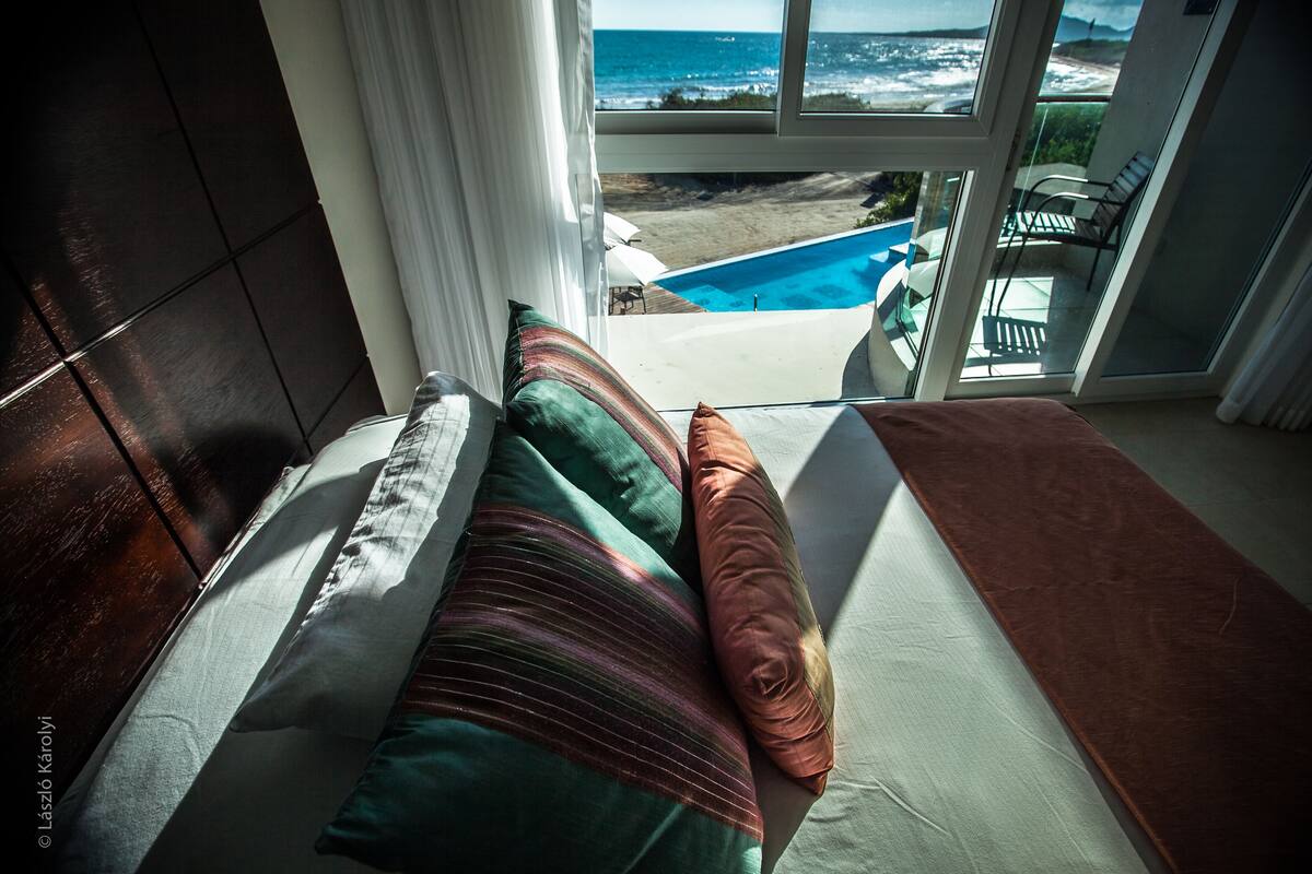 A bedroom with a view of the ocean and a pool.