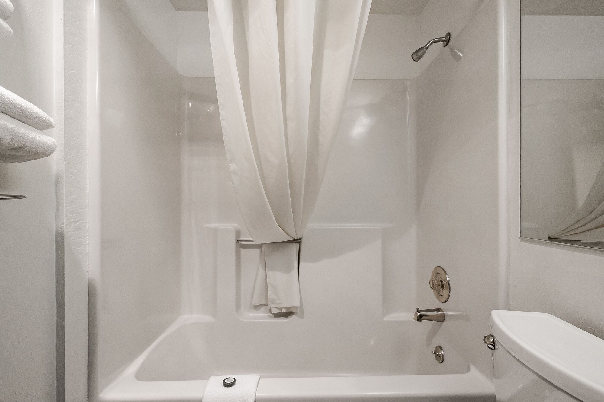 A white bathroom with a bathtub, a shower, and a toilet.