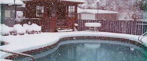 A snow-covered outdoor area with a swimming pool, wooden deck, and a wooden fence. - Aladdin Inn (Sonora)
