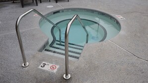Una piccola piscina all'aperto con una profondità massima di 90 centimetri, circondata da un solarium in cemento e dotata di scalette metalliche.