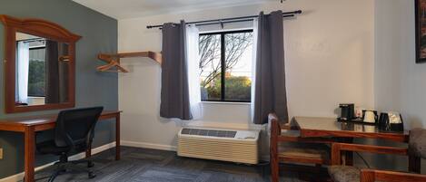 A room with a desk, chair, and a window with curtains.