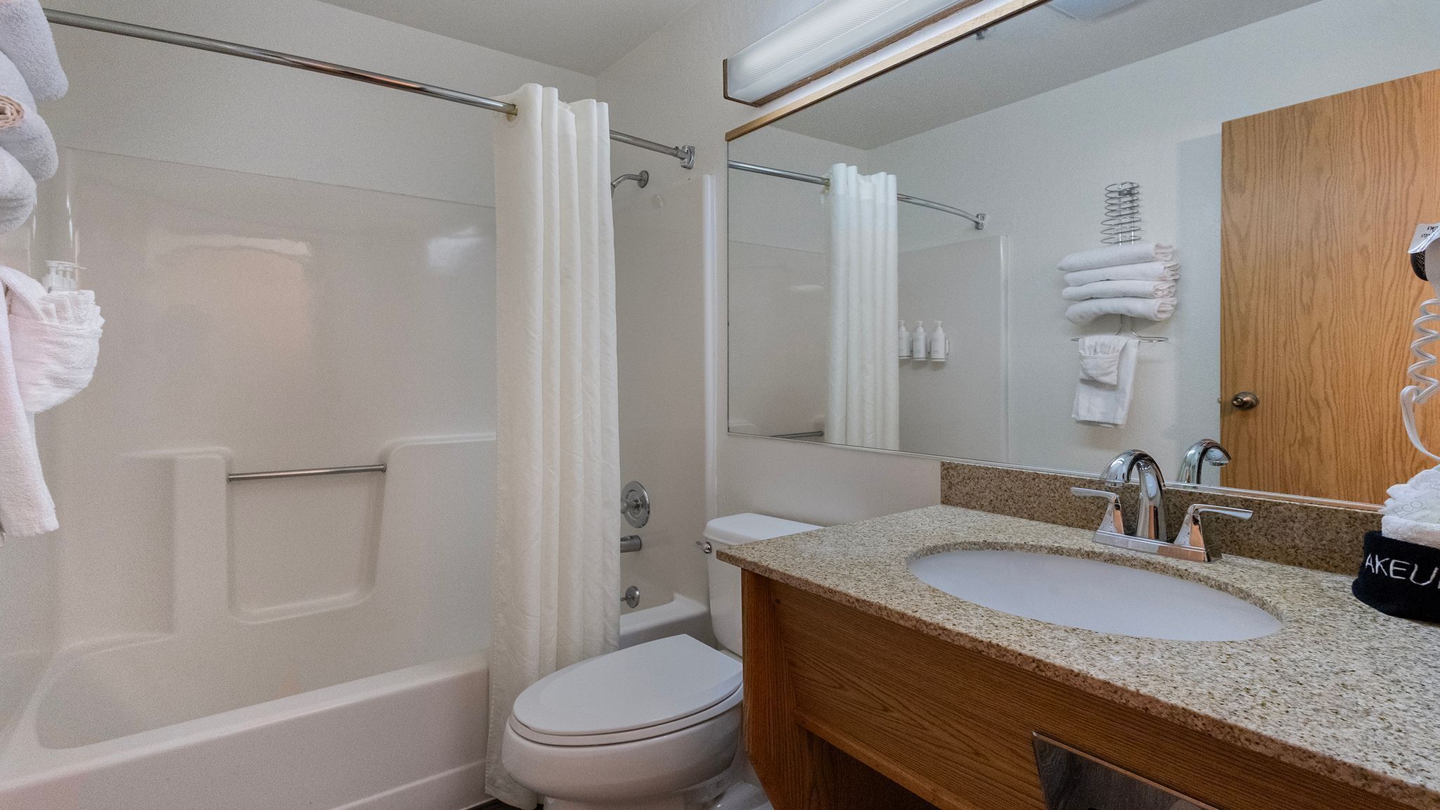 A modern bathroom with a glass-enclosed shower, a toilet, and a sink with a wooden vanity.