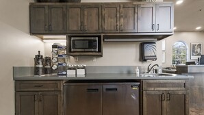 A kitchen with dark wooden cabinets, a stainless steel dishwasher, a microwave, and a coffee machine.