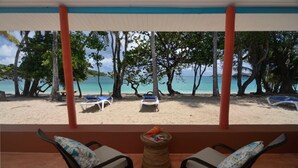 A beach view from a covered area with two chairs and a small table. - Sugarapple Inn (Bequia Island)