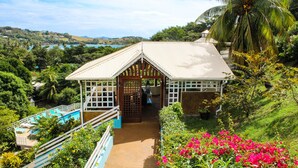 A resort with a pool, a covered entrance, and a view of the surrounding landscape. - Sugarapple Inn (Bequia Island)