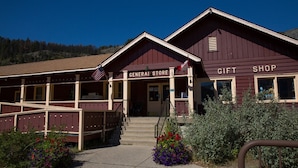 A building with a 'General Store' and 'Gift Shop' sign, featuring a wooden exterior, a porch, and steps leading to the entrance. - Rising Sun Motor Inn and Cabins - Inside the Park (East Glacier Park)