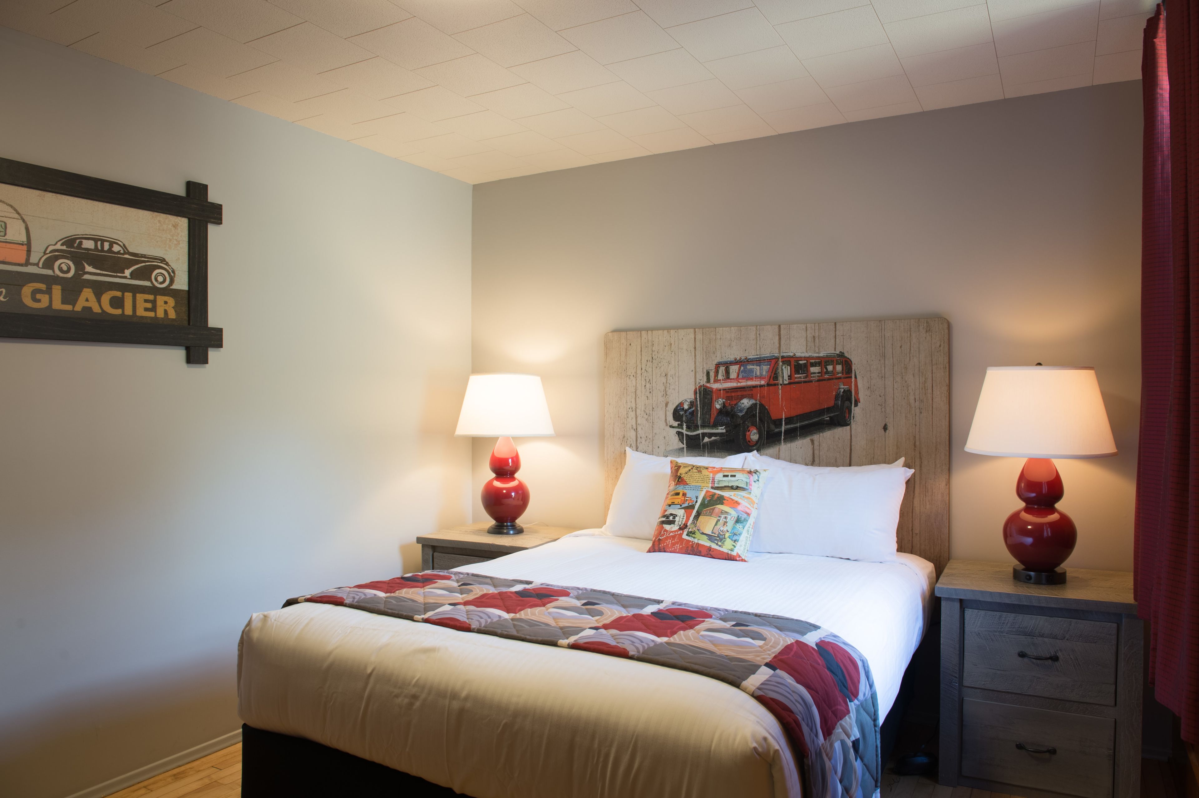 A hotel room with a bed, two bedside tables with lamps, a wooden headboard, and a wall-mounted sign.