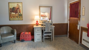 A hotel room with a desk, chair, and a red toy bus. - Rising Sun Motor Inn and Cabins - Inside the Park (East Glacier Park)
