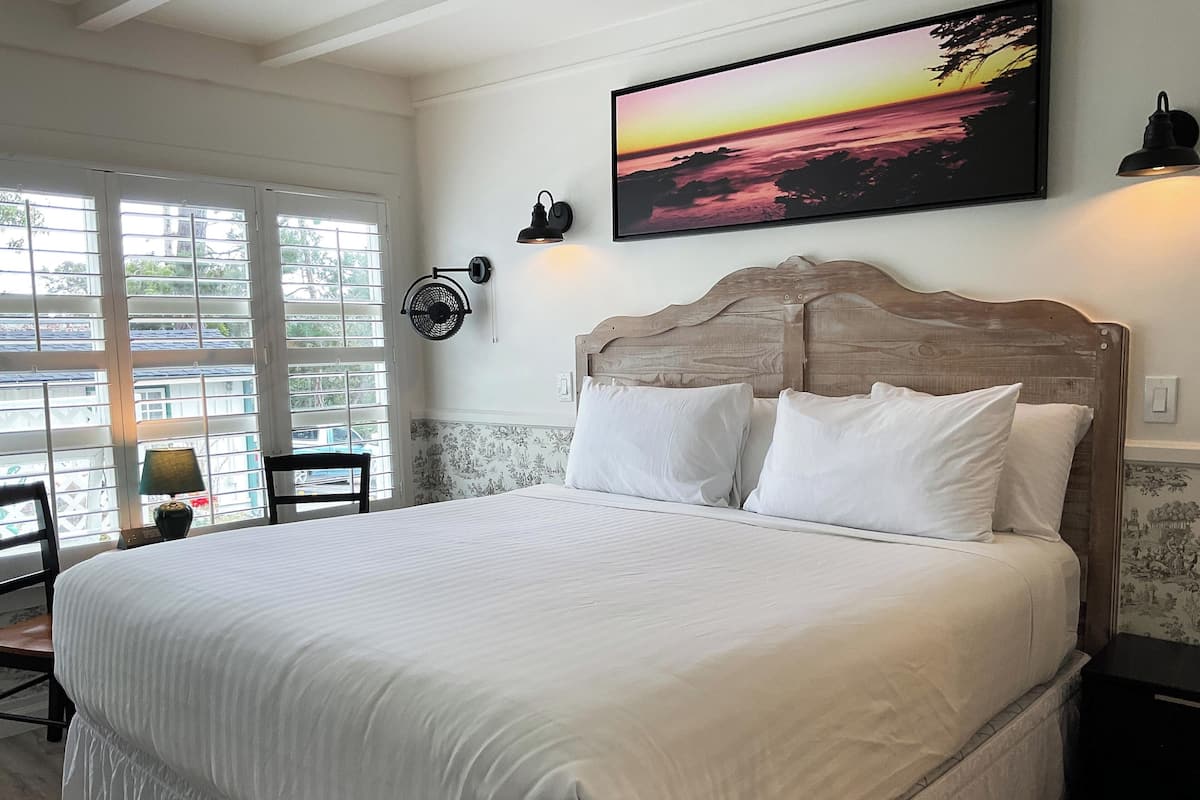 A neatly made bed with white linens, a wooden headboard, and two wall-mounted lamps.