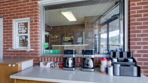 Ein Ladentresen mit zwei Kaffeeautomaten, ein Fenster mit einem Schild und verschiedenen Kaffeeprodukten.