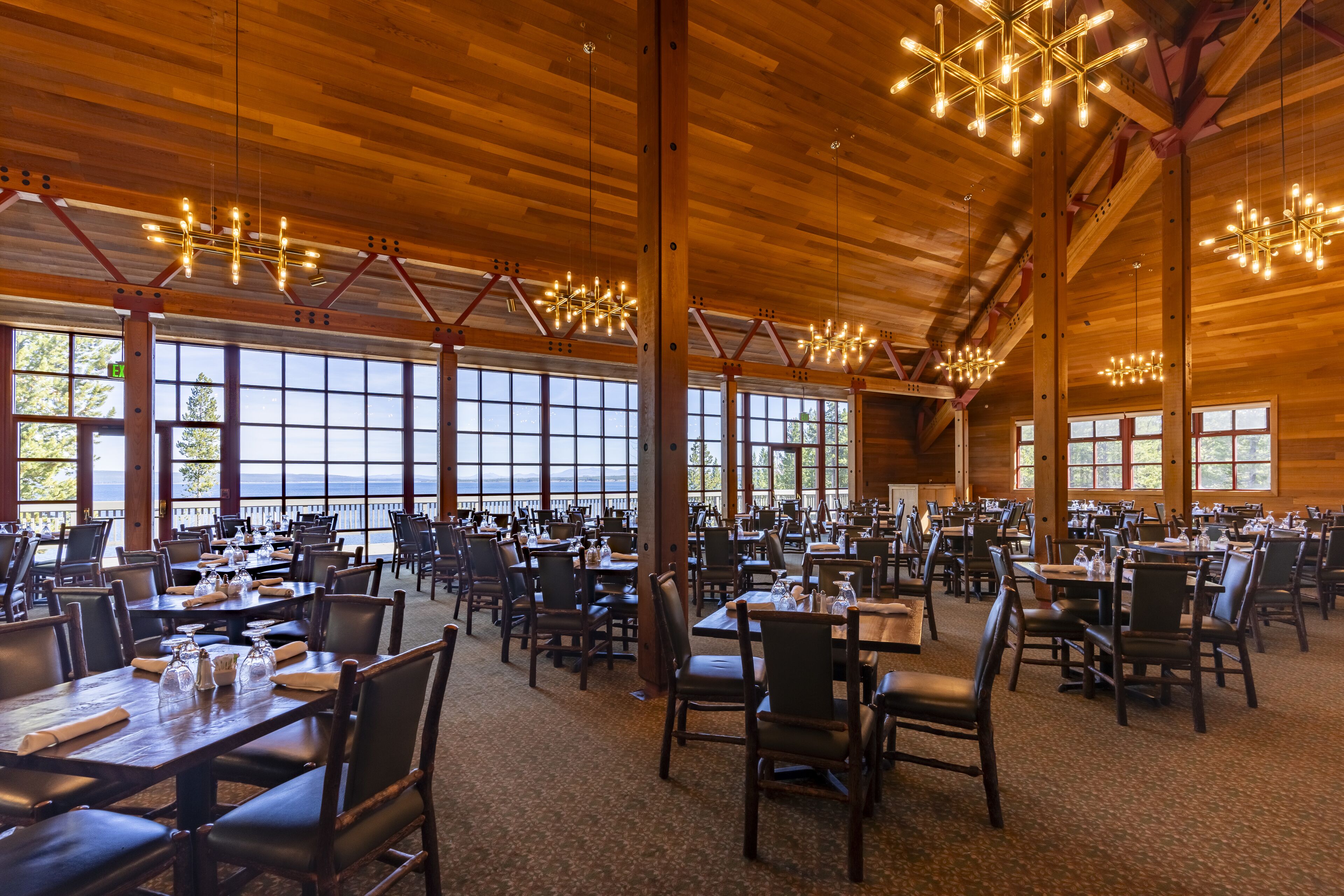 A spacious dining area with high ceilings and large windows, featuring wooden beams and modern lighting fixtures.