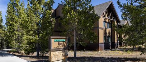 A lodge with a stone sign indicating it's part of the Grand Village in Yellowstone National Park.