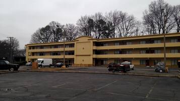 A multi-story motel with a parking lot in front.