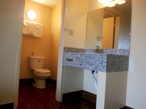 A bathroom with a toilet, sink, mirror, and a towel hanging on the wall.