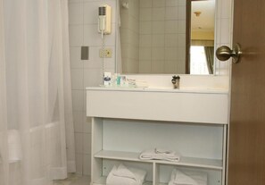 Ein Badezimmer mit weißem Waschbecken, einem Spiegel, einem Fön und einem Handtuchhalter.