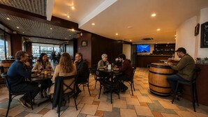 Un restaurante con varias mesas y sillas, una zona de bar y una pantalla de televisión.