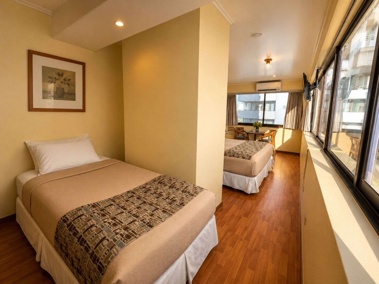 Une chambre d’hôtel avec deux lits, un coin repas et une grande fenêtre.