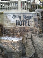 Una cascada con un letrero que dice "Kelly Rogers HOTEL" frente a un muro de piedra.