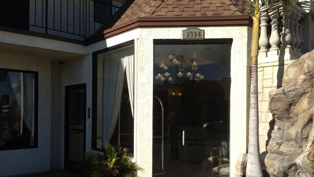 A building entrance with a glass door, a potted plant, and a stone wall. - Jolly Roger Hotel (Marina del Rey)