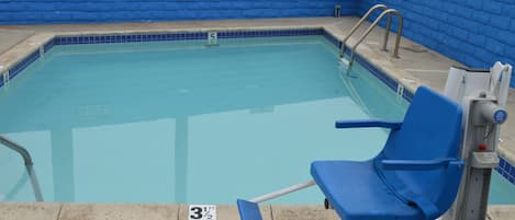 Una piscina al aire libre, sillones reclinables de piscina